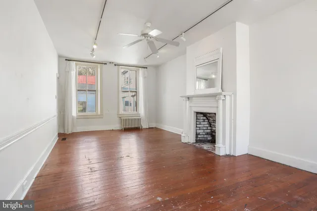 a view of an empty room with wooden floor and a fireplace