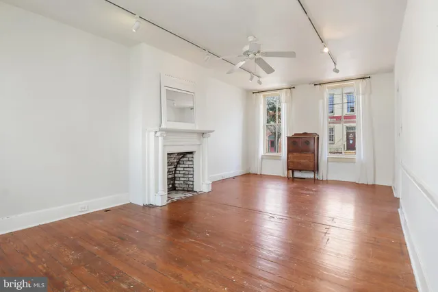 a view of an empty room with window and wooden floor