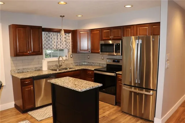 a kitchen with granite countertop kitchen island stainless steel appliances a refrigerator a stove a sink a dining table and chairs