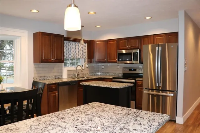 a kitchen with kitchen island a counter top space a sink stainless steel appliances and cabinets