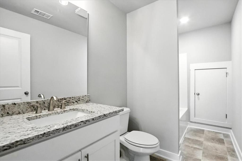 4022 Links Boulevard Jefferson, GA 30549 - Photo 41 of 54 a bathroom with a granite countertop sink a mirror and a toilet