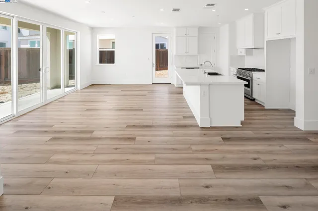 a view of a kitchen with kitchen island a sink wooden floor and a refrigerator