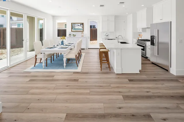 a living room with stainless steel appliances furniture a large window and a kitchen view