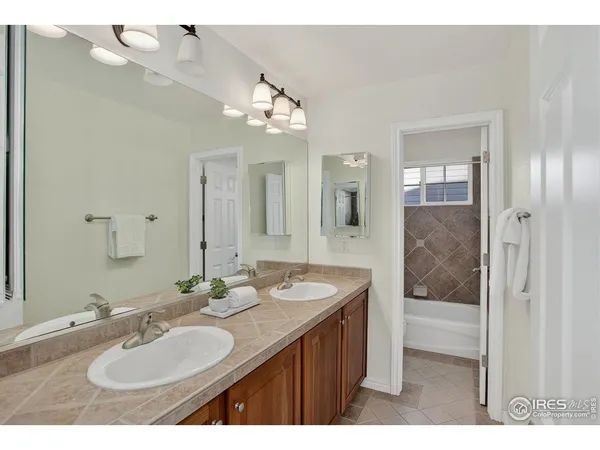 a bathroom with a sink double vanity granite tub shower and a mirror
