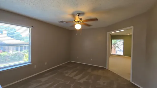 en empty room with windows and fan