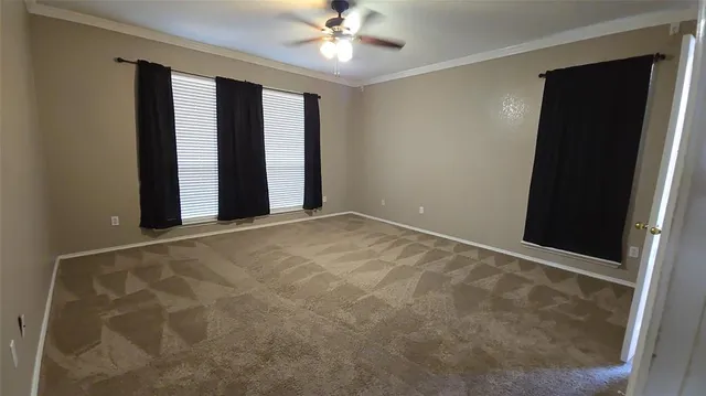 en empty room with windows and ceiling fan