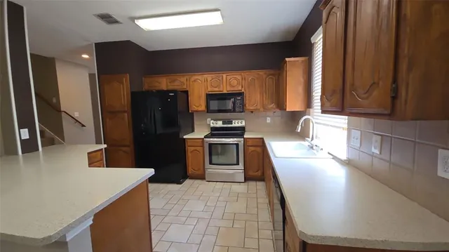 a kitchen with granite countertop a refrigerator a stove top oven a sink and dishwasher