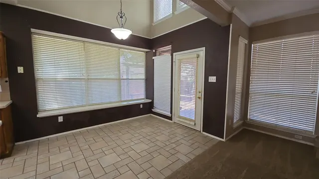 a view of an empty room with window and chandelier fan