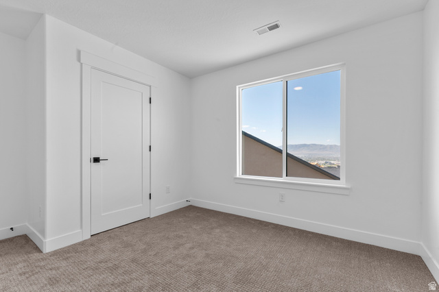 1341 West 2350 South, Unit 10 Perry, UT 84302 - Photo 16 of 18 Bright room featuring a large window, neutral carpeting, white walls, and a contemporary flat panel door with black hardware