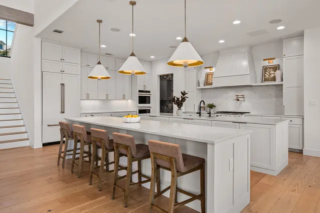 a kitchen with stainless steel appliances granite countertop a stove a sink a oven a dining table and chairs with wooden floor