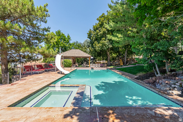 4093 North Imperial Way Provo, UT 84604 - Photo 79 of 96 Rectangular swimming pool featuring an integrated spa, an attached slide, and a surrounding paver patio