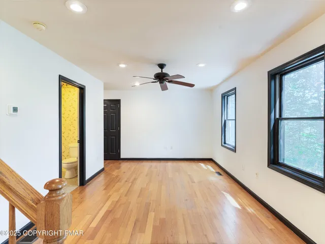 a view of an empty room with window and wooden floor