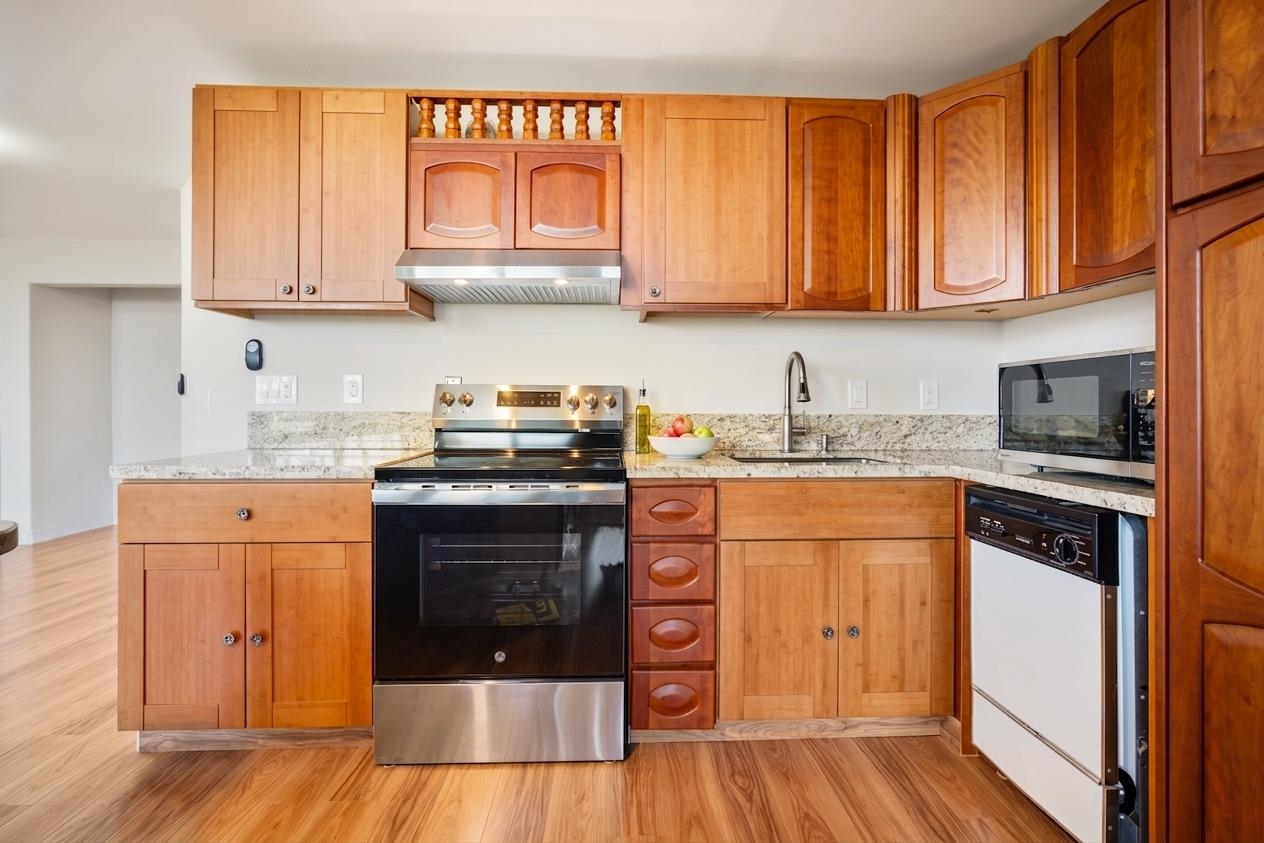 1002 South Kihei Road, Unit 114 Kihei, HI 96753 - Photo 19 of 50 a kitchen with stainless steel appliances granite countertop a stove a sink dishwasher and a refrigerator with wooden cabinets