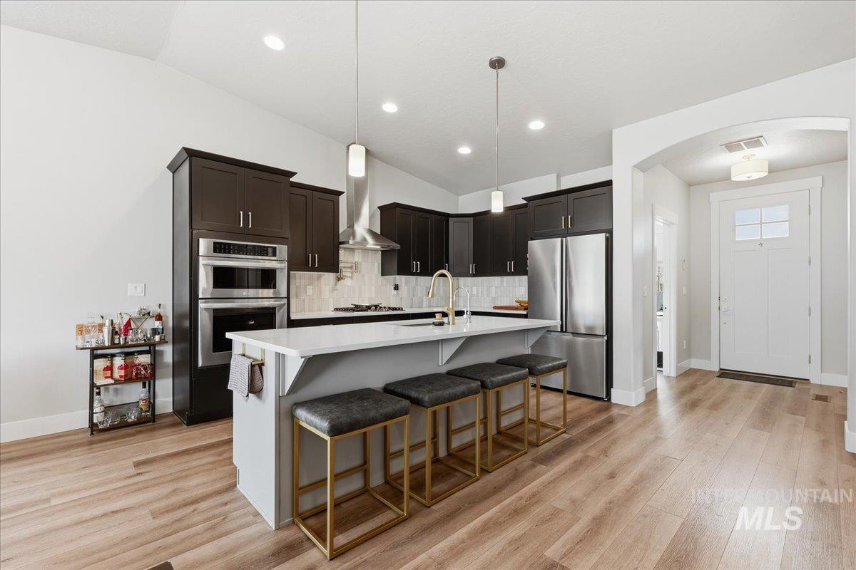 305 Tiffany Rose Way Wilder, ID 83676 - Photo 9 of 31 Kitchen with decorative light fixtures, a kitchen breakfast bar, vaulted ceiling, stainless steel appliances, and light wood-style floors