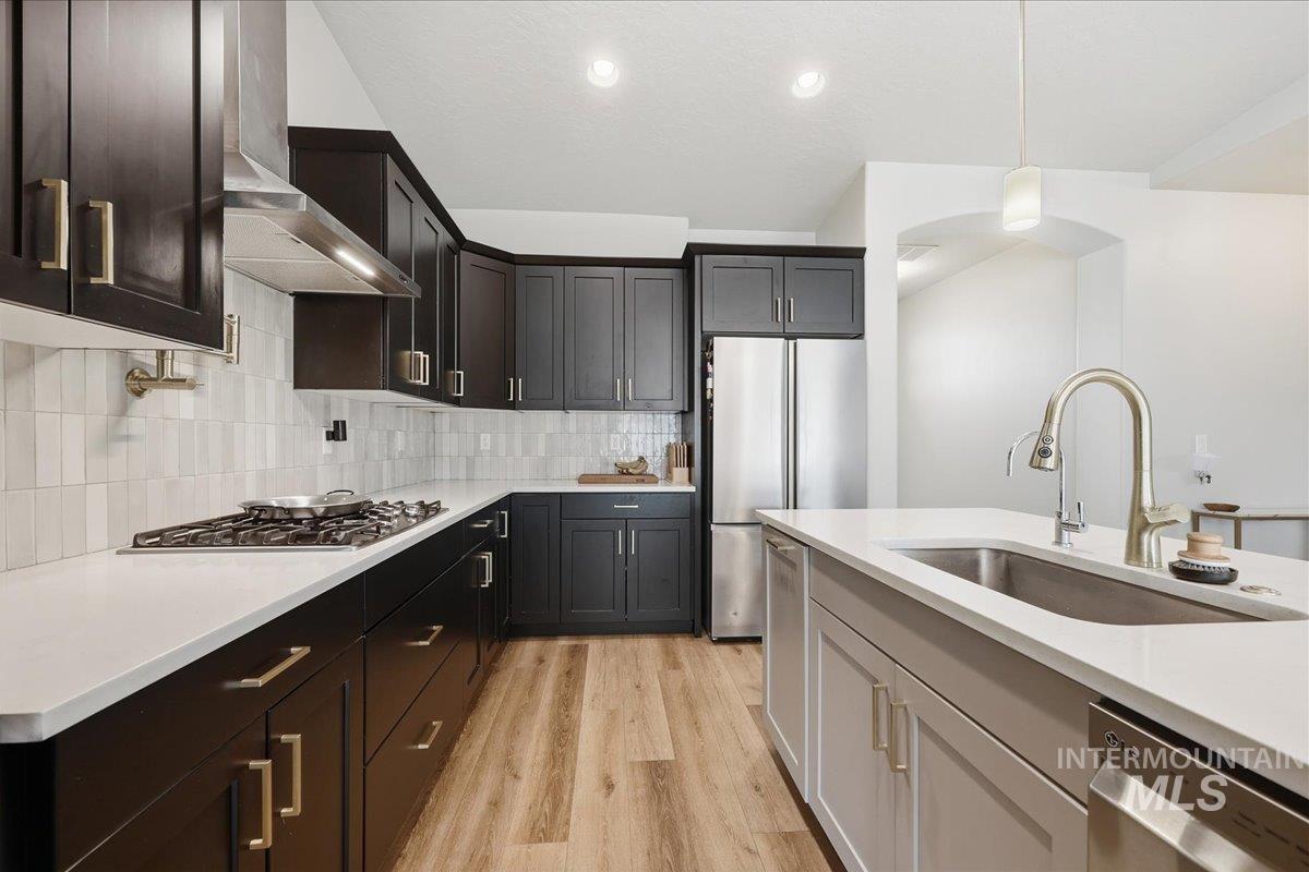 305 Tiffany Rose Way Wilder, ID 83676 - Photo 11 of 31 Kitchen with stainless steel appliances, light wood-style floors, decorative light fixtures, light stone countertops, and two tone cabinets