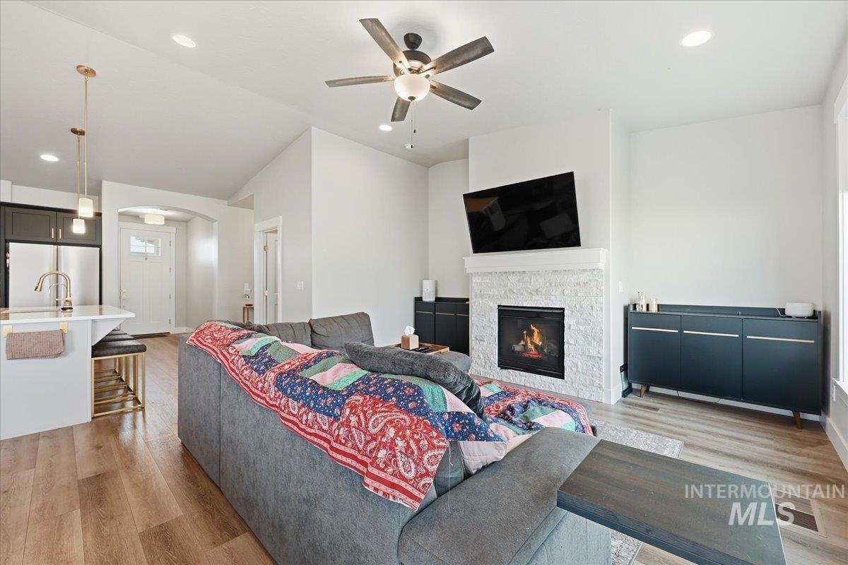 305 Tiffany Rose Way Wilder, ID 83676 - Photo 14 of 31 Living room featuring light wood finished floors, recessed lighting, a fireplace, arched walkways, and a ceiling fan