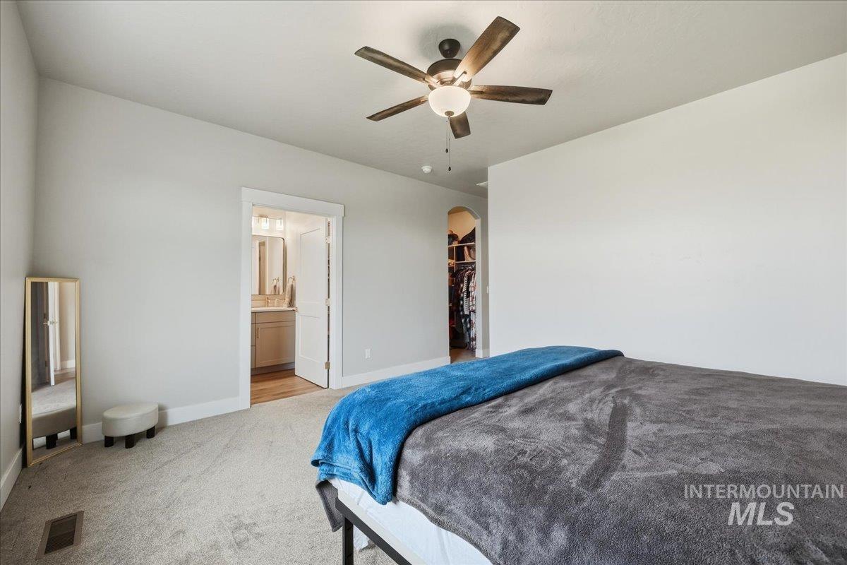 305 Tiffany Rose Way Wilder, ID 83676 - Photo 24 of 31 Bedroom with carpet flooring, ceiling fan, arched walkways, a spacious closet, and connected bathroom