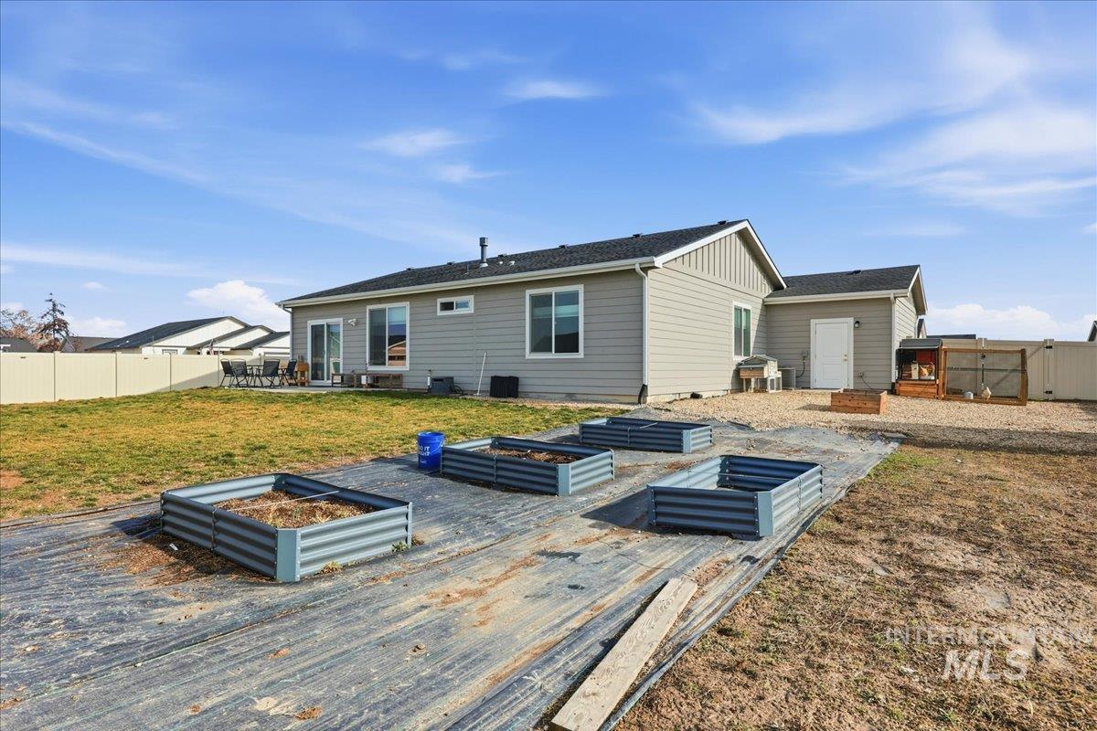 305 Tiffany Rose Way Wilder, ID 83676 - Photo 27 of 31 Rear view of house featuring a vegetable garden, a patio, a fenced backyard, and a gate