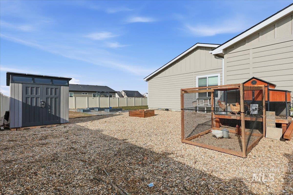 305 Tiffany Rose Way Wilder, ID 83676 - Photo 28 of 31 Fenced yard featuring exterior structure, a storage shed, and a garden