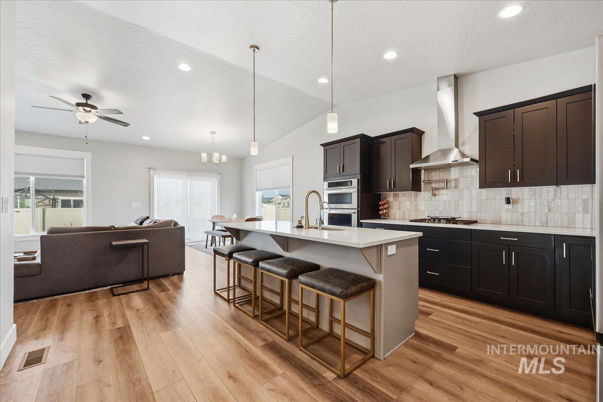 305 Tiffany Rose Way Wilder, ID 83676 - Photo 30 of 31 Kitchen with a kitchen breakfast bar, open floor plan, a kitchen island with sink, backsplash, and light wood-type flooring