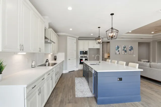a large white kitchen with a sink a center island and stainless steel appliances