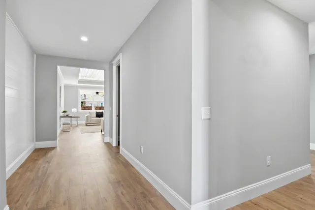 a view of a hallway with wooden floor a glass door and a bathroom