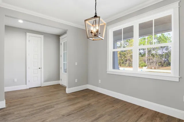 a view of an empty room with wooden floor and windows