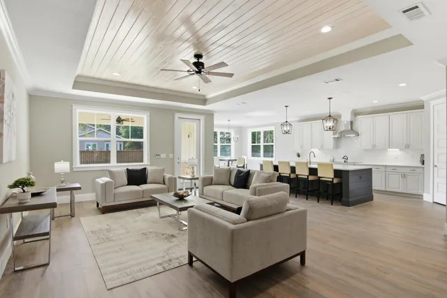 a living room with furniture kitchen view and a large window