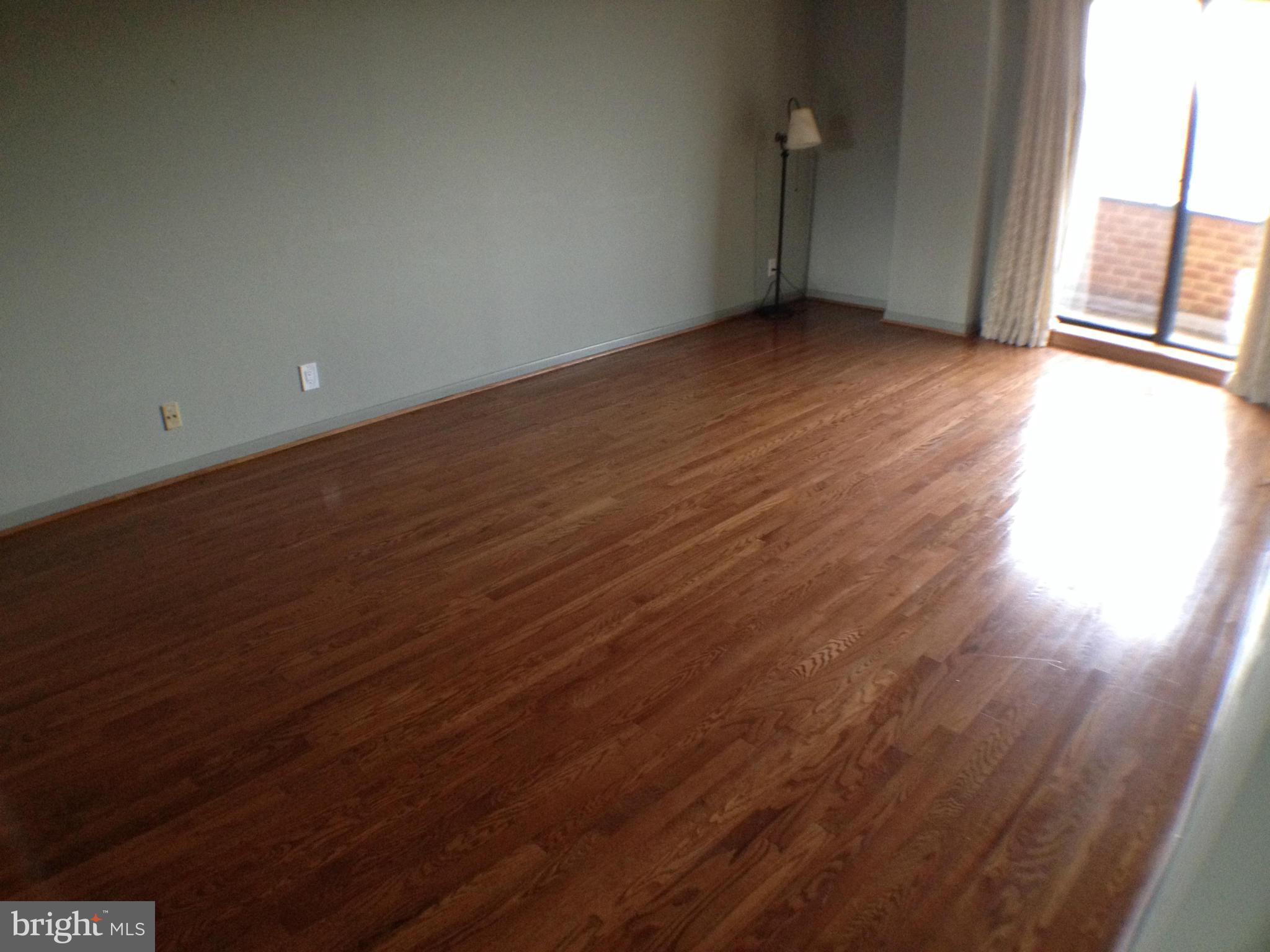 111 Hamlet Hill Road, Unit 902 Baltimore, MD 21210 - Photo 12 of 30 an empty room with wooden floor and windows