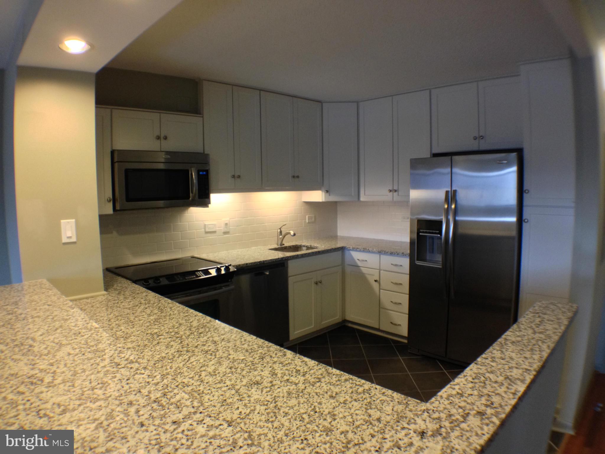 111 Hamlet Hill Road, Unit 902 Baltimore, MD 21210 - Photo 6 of 30 a kitchen with granite countertop a refrigerator and a stove top oven