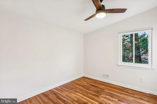 an empty room with a window and a ceiling fan