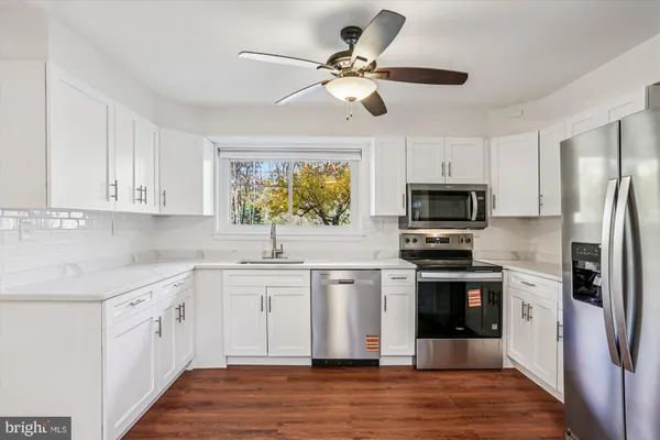 a kitchen with white cabinets stainless steel appliances and a window