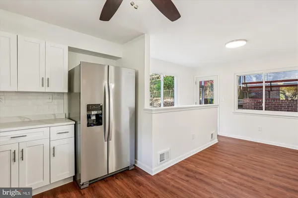 a kitchen with white cabinets and wooden floor
