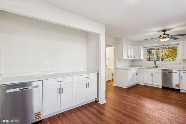 a kitchen with white cabinets and wooden floors