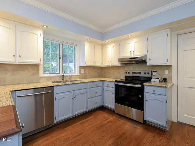 a view of a livingroom with a chandelier wooden floor and windows