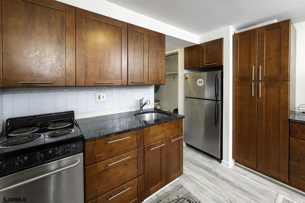 9201 Atlantic Avenue, Unit 18 Margate City, NJ 08402 - Photo 3 of 12 a kitchen with granite countertop wooden cabinets and a stove top oven