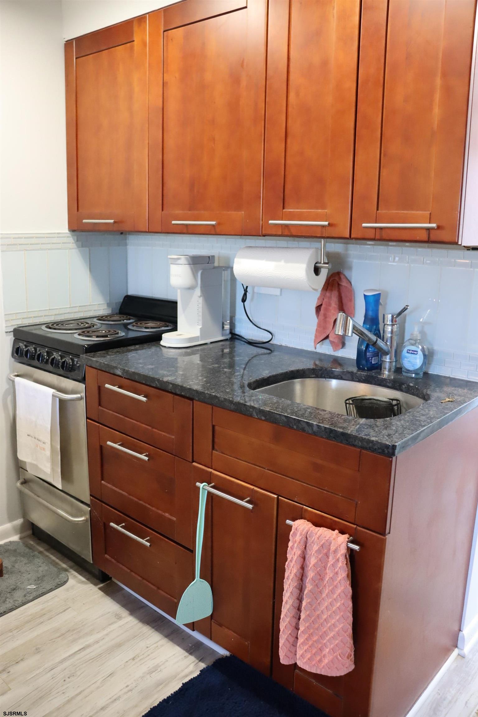 9201 Atlantic Avenue, Unit 18 Margate City, NJ 08402 - Photo 4 of 12 a kitchen with granite countertop wood cabinets and stainless steel appliances