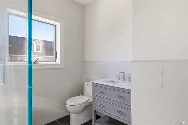 a bathroom with a toilet sink vanity and mirror