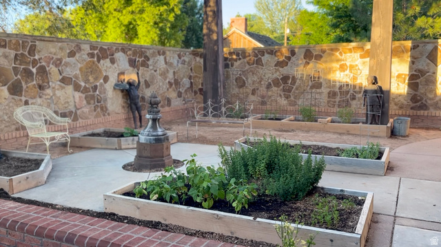 426 West Center Street Parowan, UT 84761 - Photo 87 of 107 Stone accent wall surrounding a patio space featuring multiple raised garden beds, a central decorative element, and a brick border