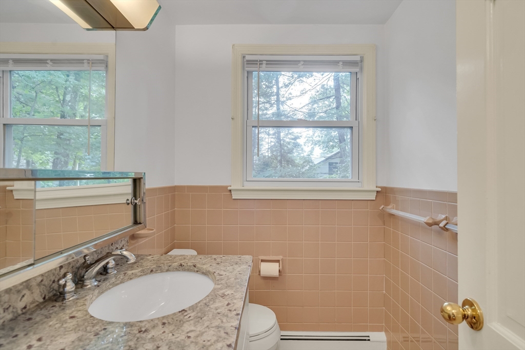 32 Dewey Road Lexington, MA 02420 - Photo 30 of 32 a bathroom with a granite countertop sink a mirror a window and a shower