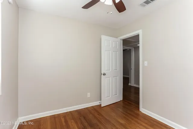 an empty room with ceiling fan and wooden floor