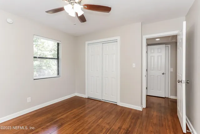 a view of an empty room with wooden floor and a window