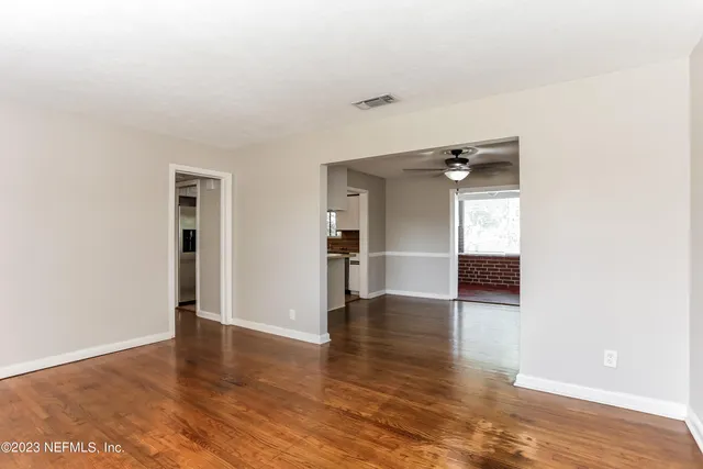 a view of a hallway with wooden floor and a living room