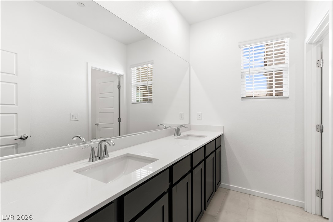 320 Isla Enclave Way Henderson, NV 89011 - Photo 33 of 49 A well-lit bathroom features a spacious dual vanity with sleek cabinetry and a large mirror.