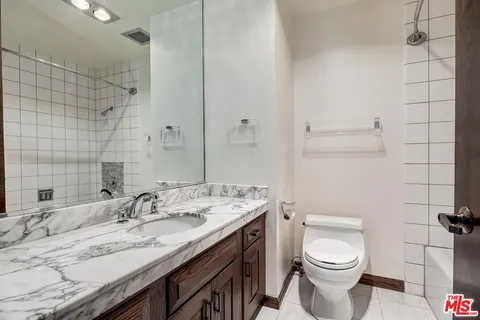 a bathroom with a granite countertop sink a toilet and a mirror
