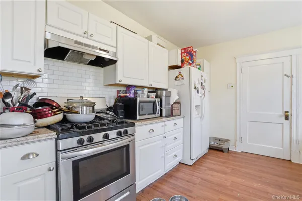 a kitchen with stainless steel appliances white cabinets and a stove top oven