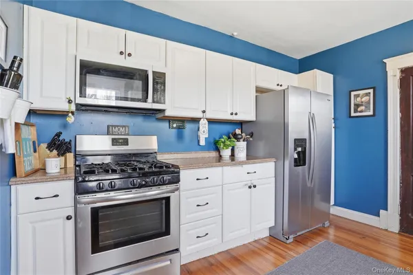 a kitchen with stainless steel appliances white cabinets and a stove a refrigerator with wooden floor