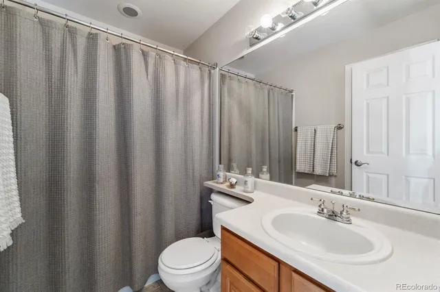 a bathroom with a sink a toilet a mirror and shower curtain