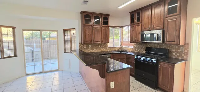 a kitchen with stainless steel appliances granite countertop a stove a sink and a microwave