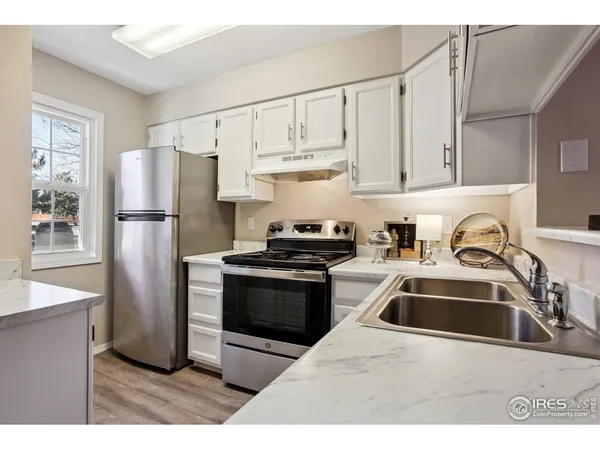 a kitchen with stainless steel appliances granite countertop a refrigerator a sink a stove and white cabinets